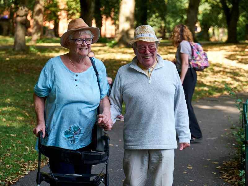 elderly woman and man walking in a park holding hands